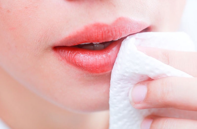 Sử dụng giấy khô để thấm sạch nước trên môi sau 6-8 giờ xăm